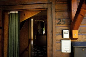 Une porte en bois portant le numéro « 25 » et un interphone fixé au mur.