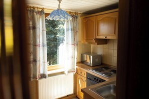 Une cuisine avec des meubles de rangement en bois, un four à micro-ondes et une cuisinière.