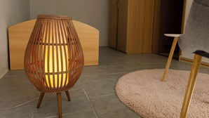A room with a wooden floor, a round, woven floor lamp, and a wooden cabinet.