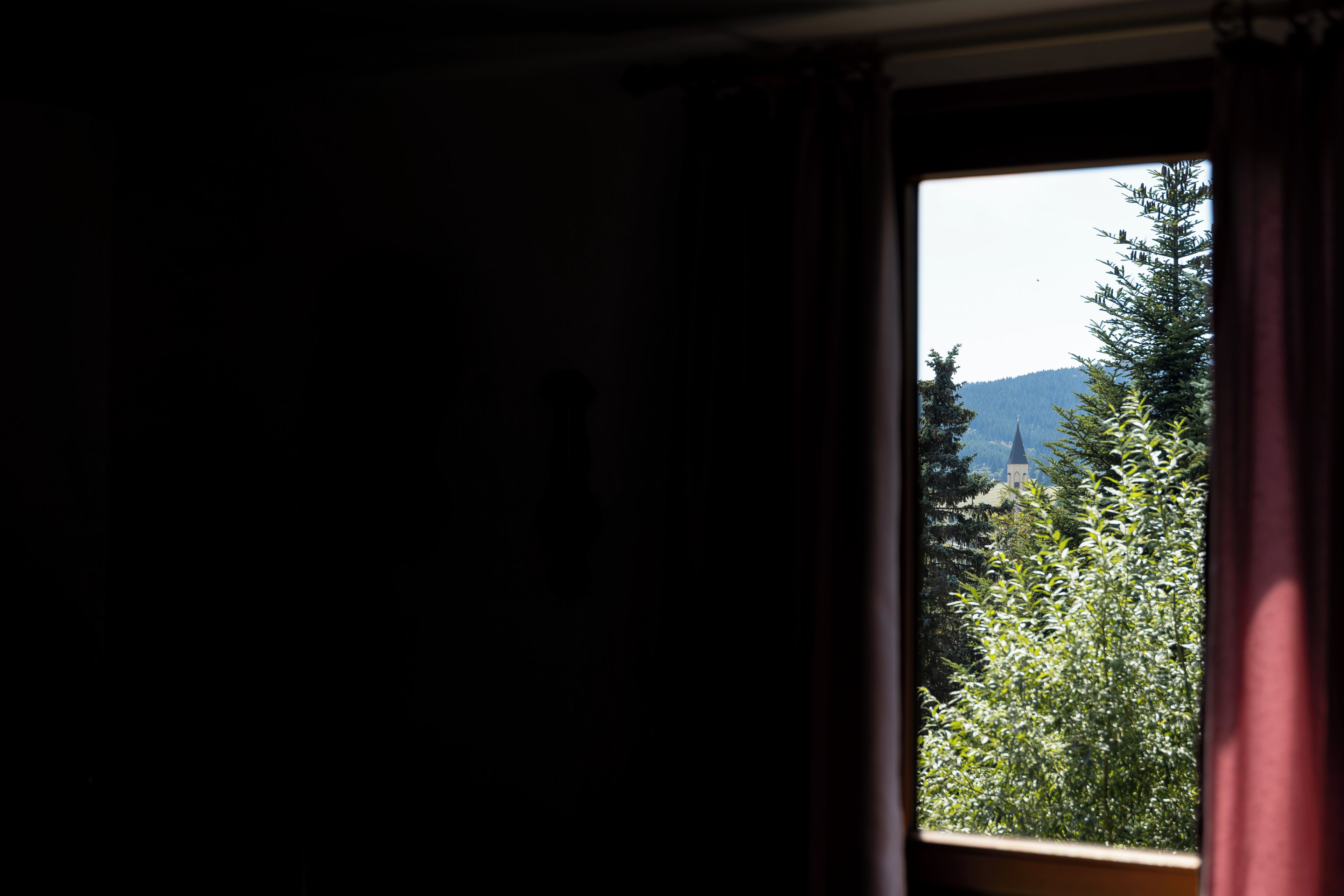 A window with a view of a church and trees.