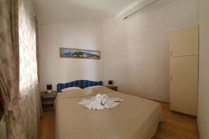 Ein Hotelzimmer mit Bett, Nachttisch, Lampe, gerahmtem Bild an der Wand und Kleiderschrank.