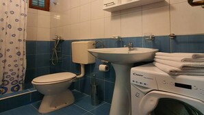 A bathroom with a toilet, sink, and washing machine. - Comfort Accommodation Baošići Montenegro-Double Room with Balcony and Sea View 2 (Baosici)