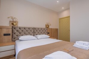 Habitación de hotel con una cama grande, dos mesitas de noche, un cabecero de madera y una puerta.