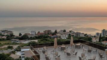 A rooftop terrace with outdoor seating and a view of the sea.