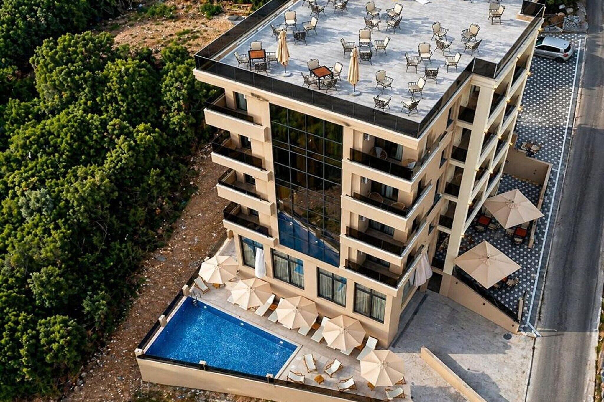 Ein mehrstöckiges Hotel mit Dachterrasse, Pool im Freien und Lounge-Bereich.
