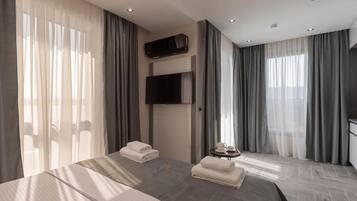A hotel room with a large bed, a flat-screen TV mounted on the wall, and a small table with a tray.