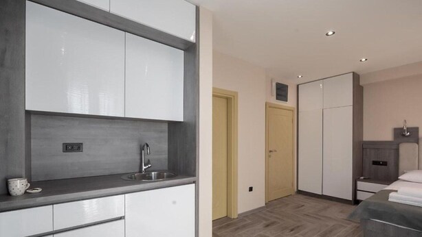 A modern kitchen with white cabinets, a stainless steel sink, and a grey countertop. - Hotel D'Iman - Classic Triple Room with Sea View and Balcony (202) (Dobra voda)