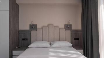 A hotel room with a large bed, two bedside tables, and a headboard with built-in lighting.