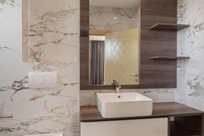 A bathroom with a marble wall, a white sink, and a mirror with a wooden frame. - Hotel D'Iman - Classic Triple Room with Sea View and Balcony (403) (Dobra voda)