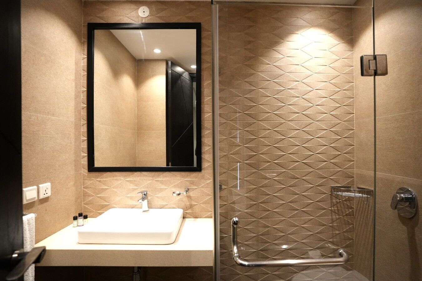 Ein modernes Badezimmer mit einer Duschkabine aus Glas, einem weißen Waschbecken und einem großen Spiegel.