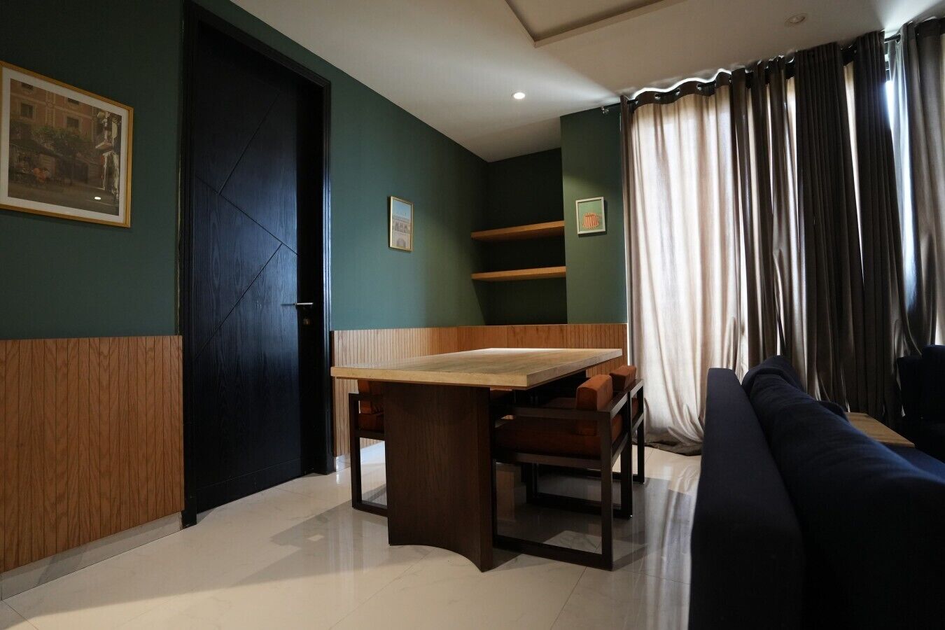 A room with a dining table, chairs, a sofa, a door, and a window with curtains.