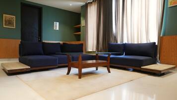 A modern living room with two sofas, a glass coffee table, and a door.