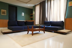 A modern living room with two sofas, a glass coffee table, and a door. - 3 BR | Pool Access | Family Friendly | Gulberg 3 (Lahore)