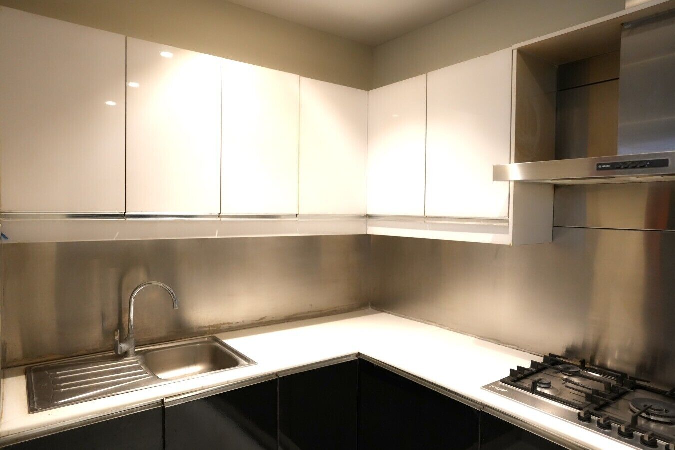 A modern kitchen with stainless steel appliances, a sink, and black cabinets.