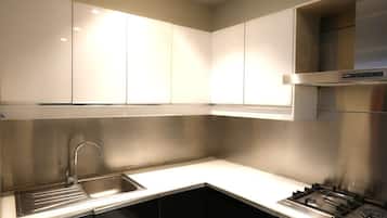 A modern kitchen with stainless steel appliances, a sink, and black cabinets.