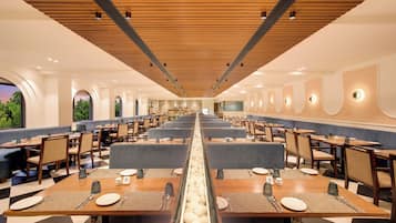 Un comedor amplio con múltiples mesas y cabinas, un pasillo central y vistas al exterior.
