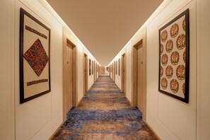 A hotel hallway with framed artwork on the walls, a patterned carpet, and wooden doors. - Lemon Tree Premier Vadodara (Vadodara)