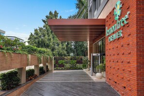 A modern building entrance with a brick facade, a green sign reading 'lemon premier', and a covered walkway with a metal roof. - Lemon Tree Premier Vadodara (Vadodara)