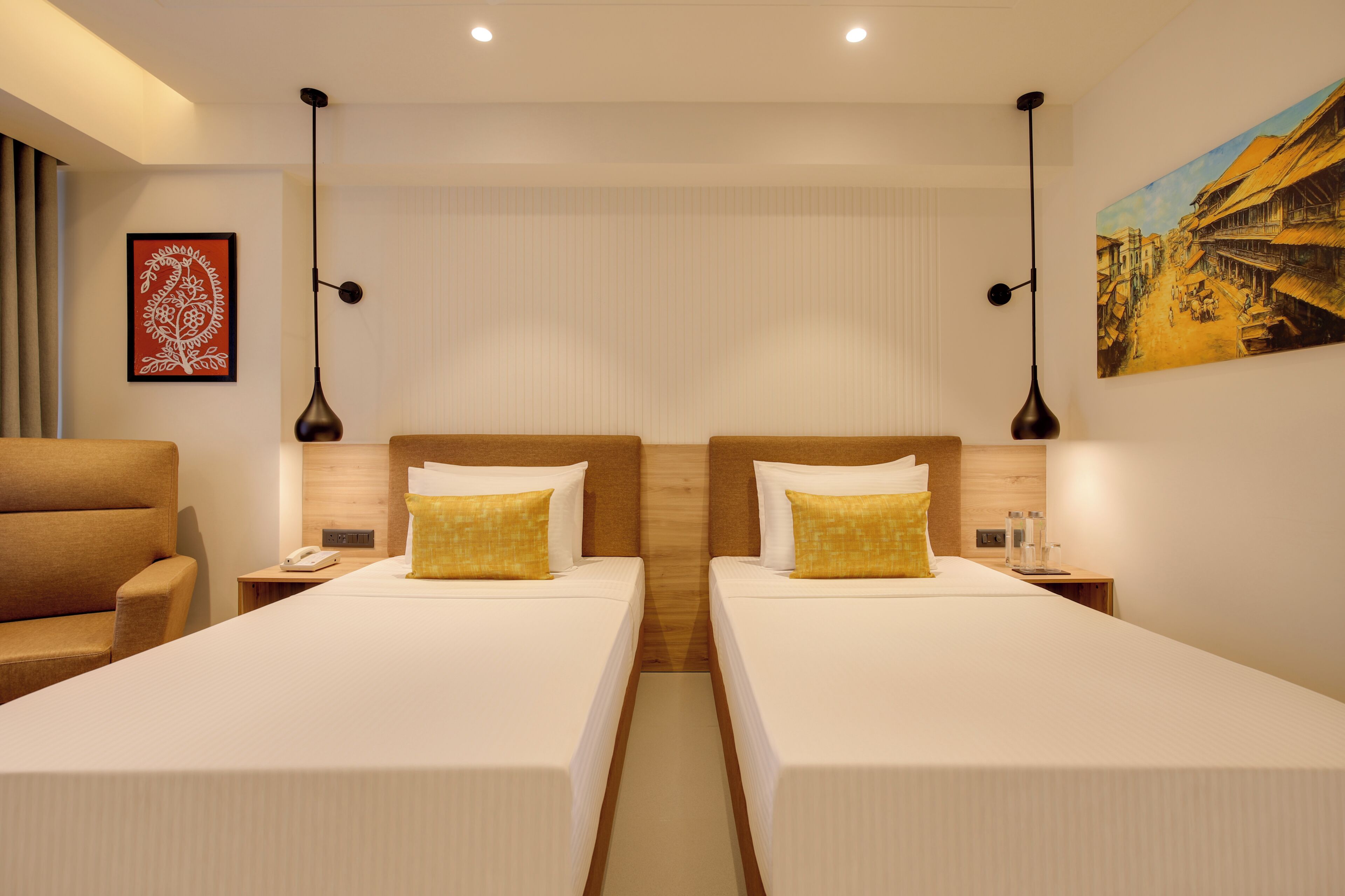 Habitación de hotel con dos camas, una mesita de noche con teléfono, una lámpara y un cuadro en la pared.