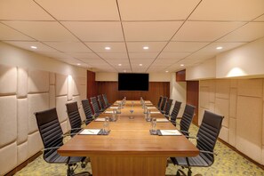 A conference room with a long table, black chairs, and a flat-screen TV. - Lemon Tree Premier Vadodara (Vadodara)