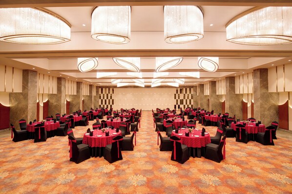 A large conference room with round tables, black chairs, and red tablecloths. - Lemon Tree Premier Vadodara (Vadodara)