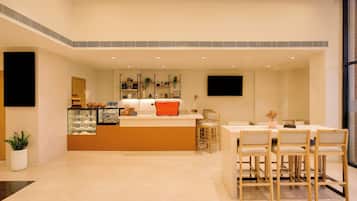 Cocina moderna con una isla central, zona de comedor con sillas de madera y un amplio ventanal que proporciona luz natural.