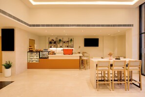 Cocina moderna con una isla central, zona de comedor con sillas de madera y un amplio ventanal que proporciona luz natural.