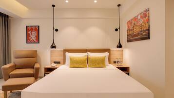 A hotel room with a large bed, a chair, a nightstand, and a painting on the wall.