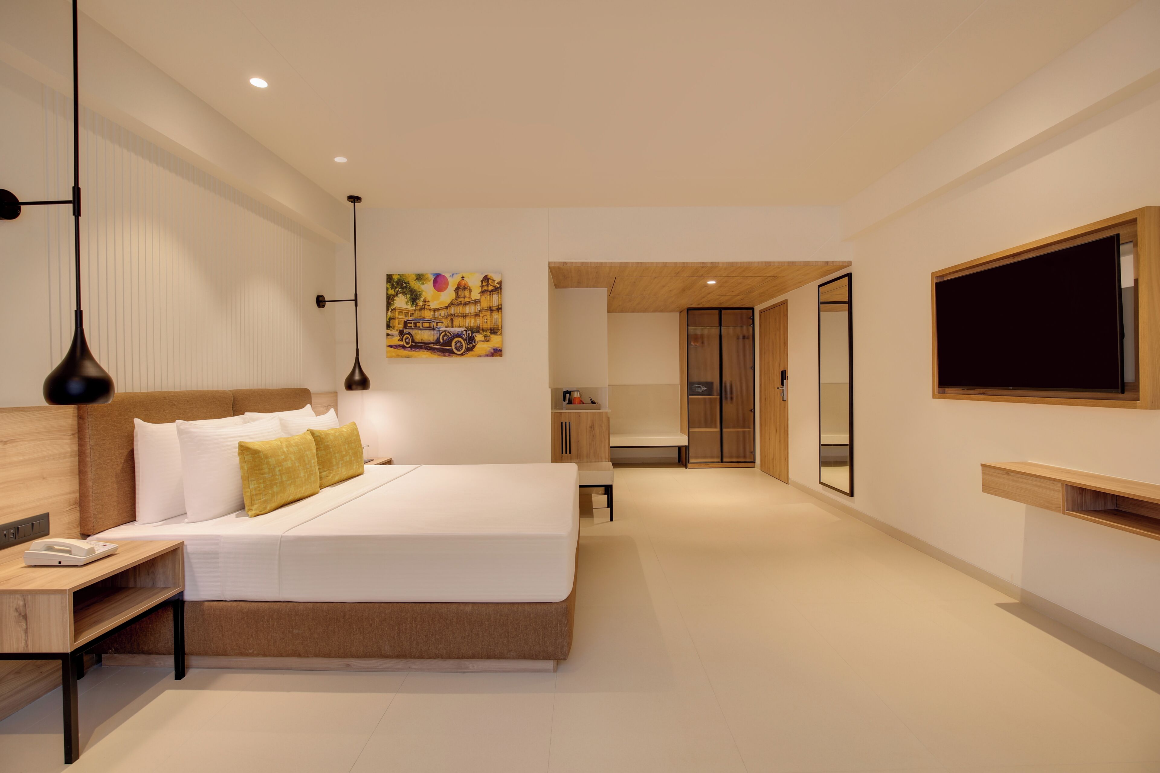 Una habitación de hotel moderna con una cama grande, mesita de noche, lámpara, una obra de arte y un televisor.