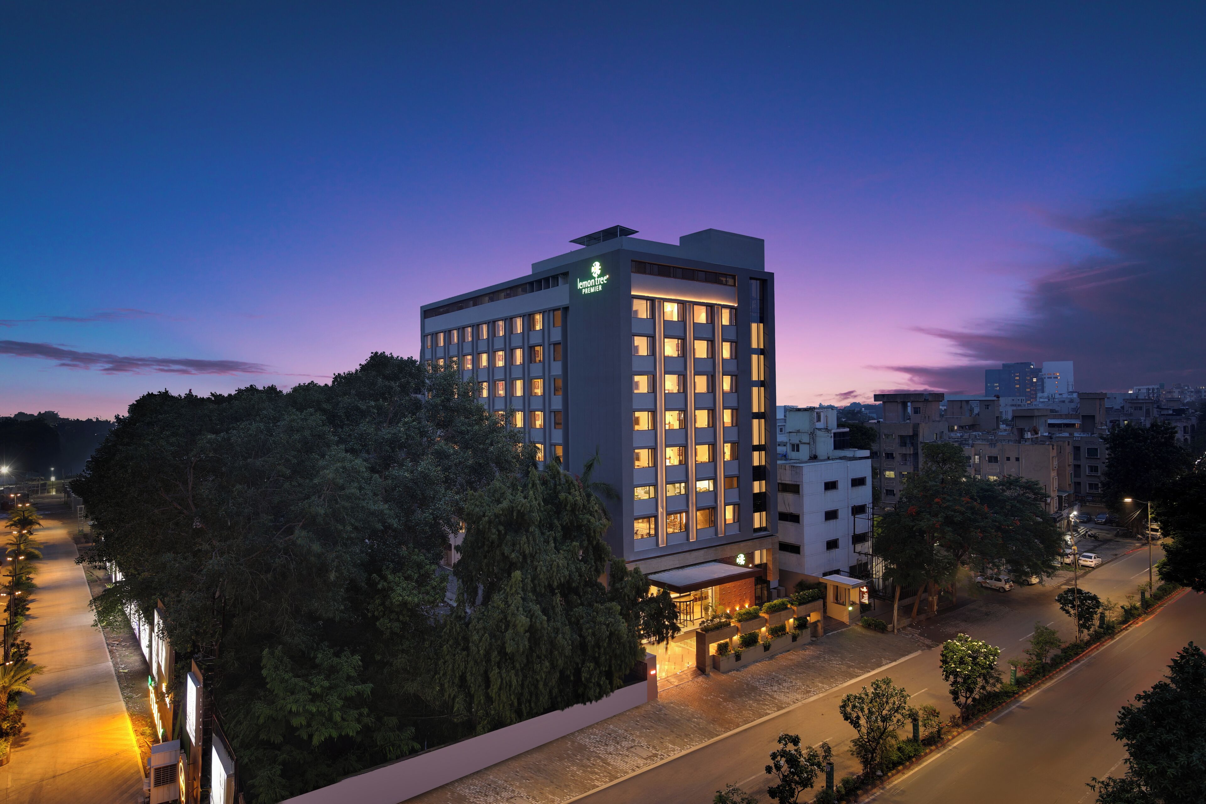 Un hotel moderno con varias plantas, ventanas amplias y una entrada bien iluminada.