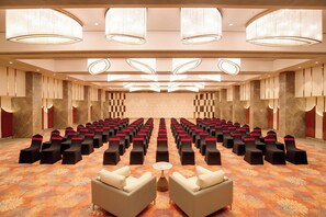 A conference room with rows of chairs, a stage, and a carpeted floor. - Lemon Tree Premier Vadodara (Vadodara)