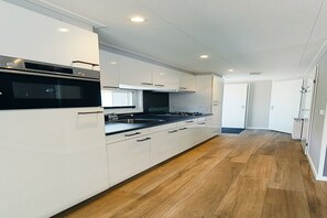 Une cuisine moderne avec des meubles blancs, un plan de travail noir et un plancher en bois.