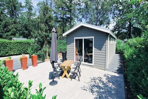 A small shed with a sliding glass door, a picnic table with chairs, and a patio umbrella.