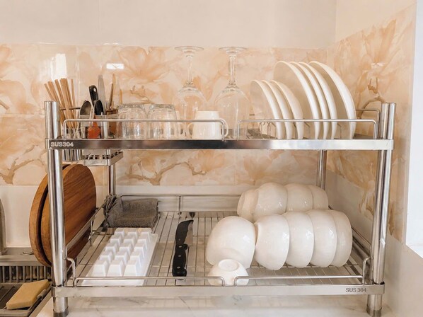 A stainless steel dish rack with multiple compartments, including a utensil holder and a section for plates and bowls.