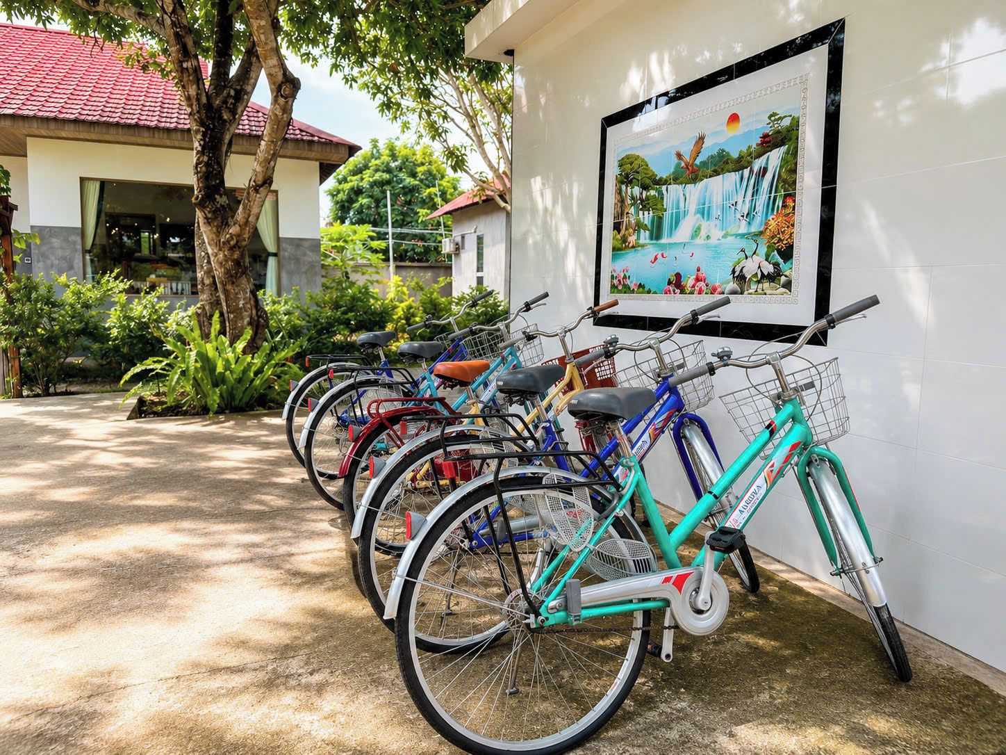 A row of bicycles parked against a wall with a framed picture above them.
