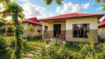 A building with a red roof, a covered porch, and a garden with stepping stones.