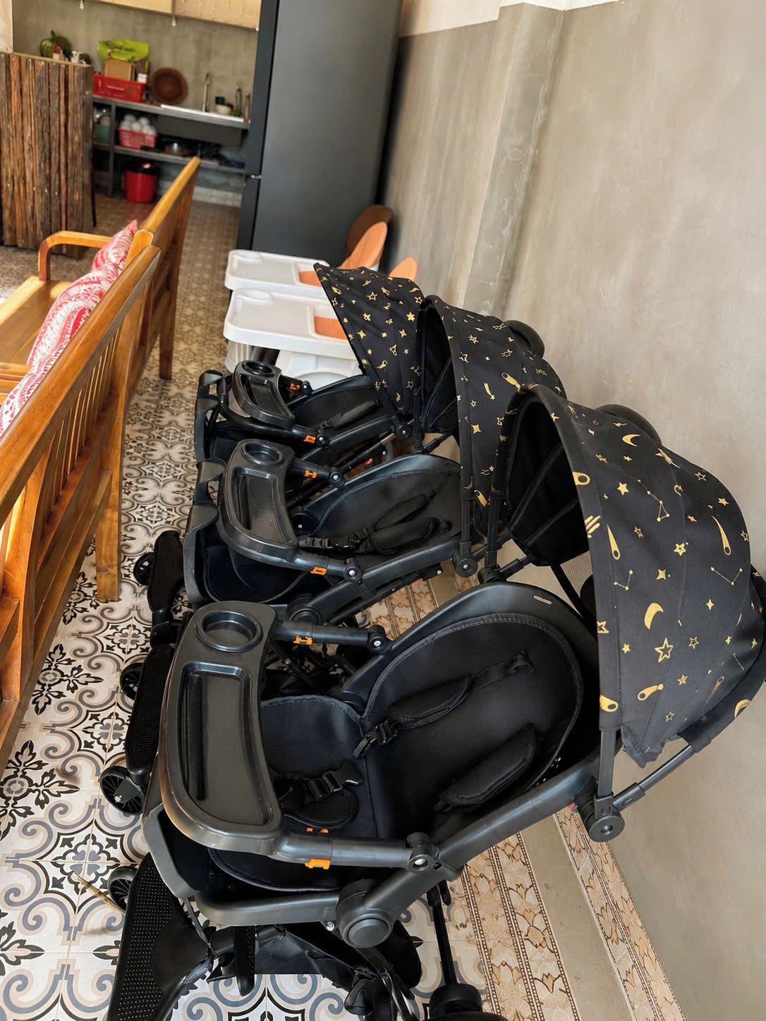 Una hilera de carriolas con funda estampada, un banco de madera y un suelo con diseño.