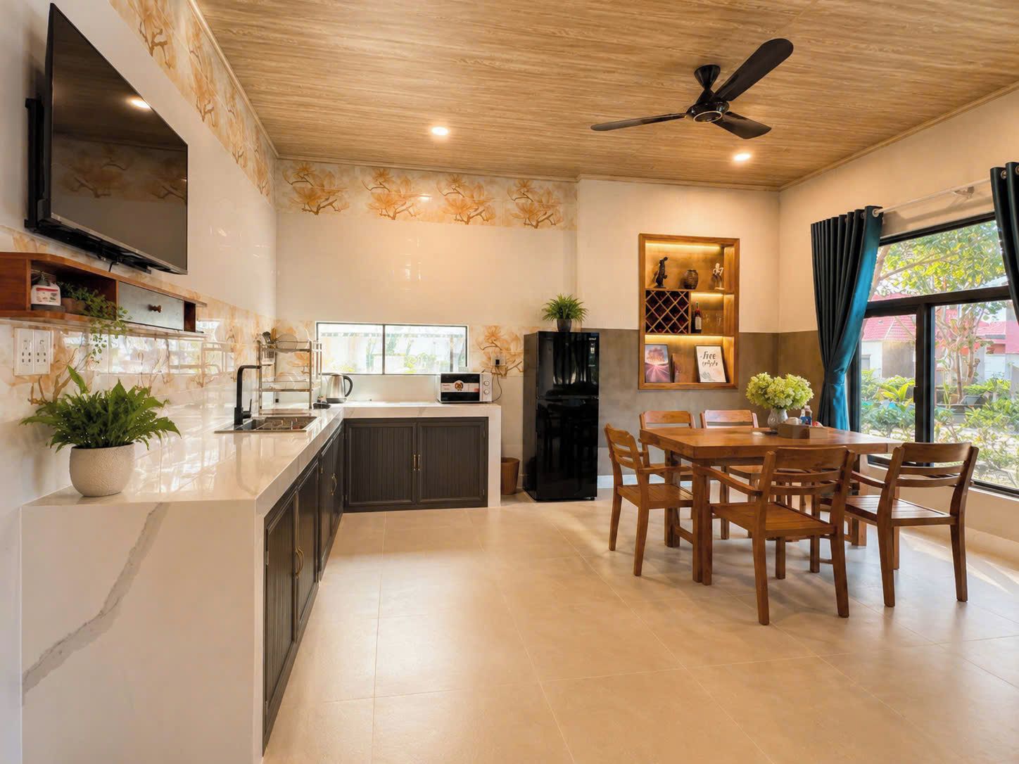 Una cocina moderna con comedor, techo de madera y televisor integrado.