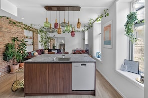 A modern kitchen with a central island, a dishwasher, and a brick wall.