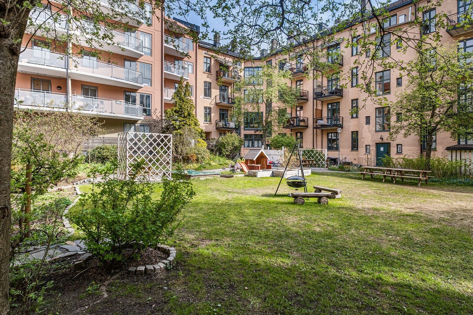 Un immeuble résidentiel doté de nombreux balcons, d’une aire de jeux et d’une cour verdoyante.