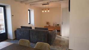 Une pièce comprenant un ensemble de canapés, une table à manger et un luminaire suspendu.