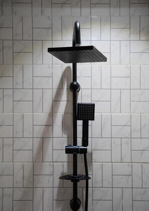 Ducha vertical negra con múltiples cabezales sobre una pared con azulejos.