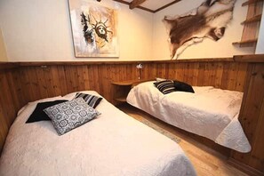 Ein Zimmer mit zwei Betten, Holzwandverkleidung und einem Bild an der Wand.