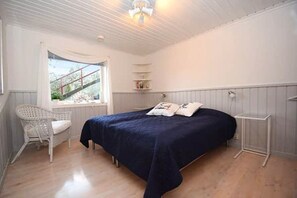 Ein Schlafzimmer mit einem Bett, einem Sessel, einem Fenster und einer Heizung.