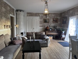 Ein Wohnzimmer mit einer Couch, einem Couchtisch, einem Kamin, einer Kristallleuchter und einer Tür.