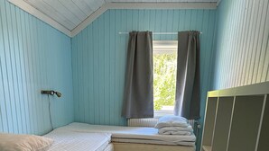 Quarto com duas camas, um radiador e uma janela com cortinas.