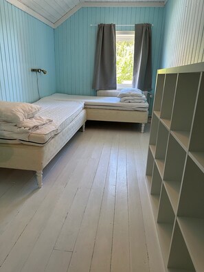 Ein Zimmer mit zwei Betten, einem Heizkörper und einem Fenster mit Vorhängen.