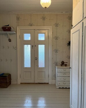 Ein Zimmer mit einer Doppeltür, einem kleinen Schminktisch und einem Regal mit einem Korb.