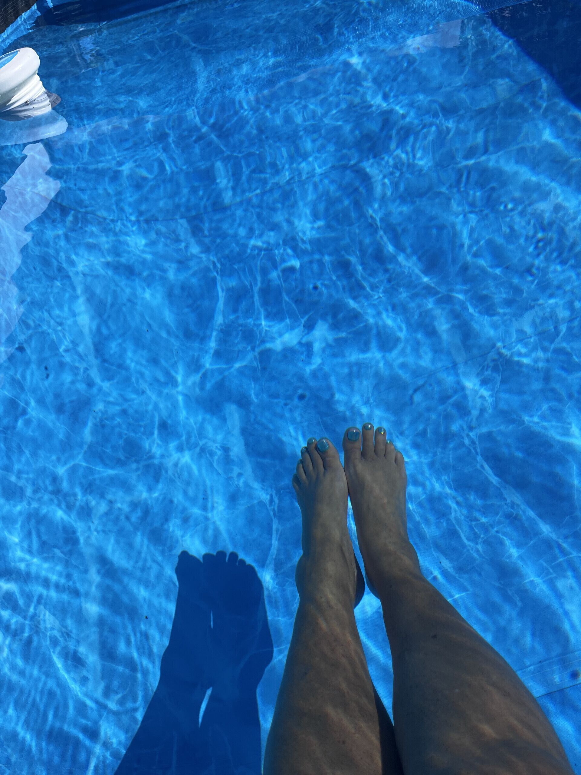 Les pieds d’une personne dans une piscine à l’eau claire.