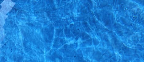 A person's feet in a swimming pool with clear water.
